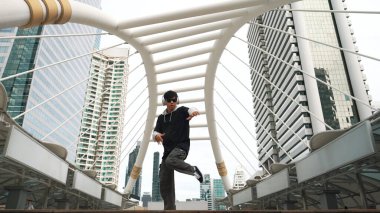 Genç Asyalı hippi şehir merkezinde insanların etrafında ayak izlerini gösteriyor. Şık bir sokak dansçısı B-boy ya da serbest dans eder. Açık hava sporu 2024. Break dans. Yumuşak bir şekilde..