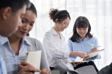 Gülümseyen Asyalı ofis çalışanı arkadaş canlısı ofis ortamında birlikte çalışıyor. İş yerinde, üretken bir ekip çalışması ve paylaşım fikri olan bir grup mutlu iş adamı. Çok titiz.