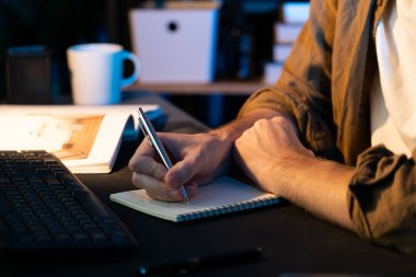 Neon Light Modern Ofis 'te yeni bir proje için tasarım üzerine düşünen genç iş adamının kırpılmış görüntüsü. E-posta ile hediye göndermeden önce not defterine yeni bir iş düşünüyorum. Toplayıcı.