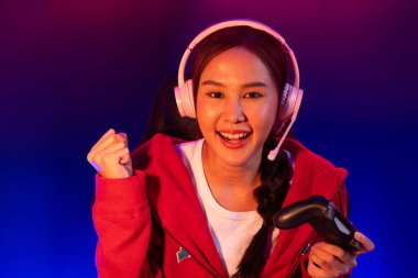 Neon odada kulaklık takan yetenekli Esport takım oyuncularını yumruklayarak oynayan güzel Asyalı kız flamasının sunucu kanalı. Taktik.