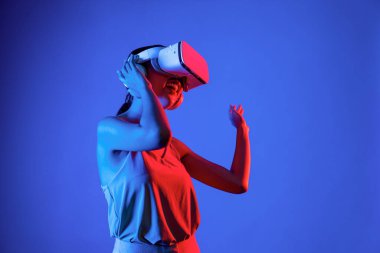 Zeki bir kadın, metaevreni birbirine bağlayan VR kulaklık takan neon ışıklarla çevrili duruyor. Gelecekteki siber uzay topluluğu teknolojisi. Zarif bir kadın dans etmekten, dans etmekten ve şarkı söylemekten hoşlanır. Halüsinasyon.