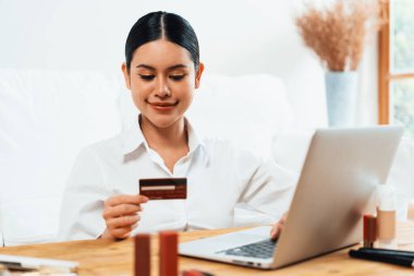 Genç mutlu Asyalı kadın internetten alışveriş yaparak ürün satın alırken aynı zamanda internetten kredi kartıyla online ödemeler sipariş ederek çevrimiçi mağaza platformundan en yüksek sanal güvenlik tarafından korunuyor.