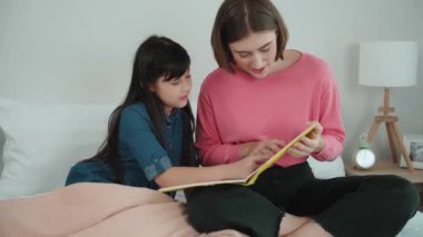 Beyaz bir anne, tatlı kızının dinlediği hikayeleri okuyor. Asyalı kız yatmadan önce hikâyeyi anlatırken işaret etti. Birlikte vakit geçirirken mutlu bir aile yatakta oturuyor. Pedagoji.