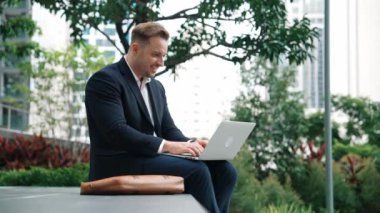 Dizüstü bilgisayarı üzerinde çalışan ve başarılı bir projeyi kutlayan ya da yeşil kentlerdeki satışları artıran bir yönetici. Profesyonel işadamı bankta otururken bilgisayar kullanarak analiz verilerine bakıyor. Urbane.