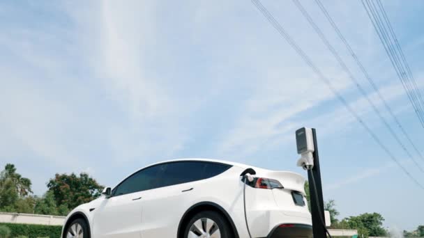 充電ステーションの遅い動きの電気自動車かEv車の充電電池は電気自動車の利用のための電気工業として送電線タワーの電気工業施設に接続します — ストック動画