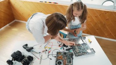Kafkas öğretmeninin öğrencilere elektronik kurulun bir parçasını öğretmesi. Uzman kız dijital elektrikli aletleri öğreniyor ve cips ve kablolarla ana kartı tamir ediyor. Etkinlik.