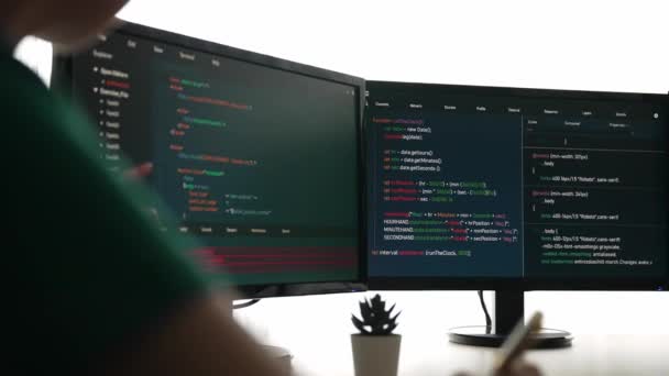 コンピュータプログラミングのためのスローモーションバックエンドソフトウェア開発エンジニアは コンピューティングコードをデバッグし オフィスのモニターに表示される複雑なアルゴリズムを解決します バージョニング — ストック動画