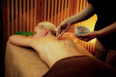 Lüks spa salonlarında sıcak mum ışığında cilt bakımı yaptıran kadın müşteri. Sağlık Spa vücut fırçasında tuz temizleme güzellik tedavisi. Sessiz.