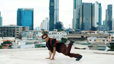 Profesyonel Asyalı break dansçı B çocuk dansı yaparken çatıda çok kültürlü arkadaşlar var. Genç modern dans grubu hip hop hareketi yapıyor. Tarz, moda, aksiyon. Açık hava sporu 2024. ÇalışmaComment.