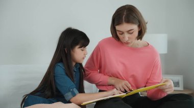 Beyaz bir anne, tatlı kızının dinlediği hikayeleri okuyor. Asyalı kız yatmadan önce hikâyeyi anlatırken işaret etti. Birlikte vakit geçirirken mutlu bir aile yatakta oturuyor. Pedagoji.