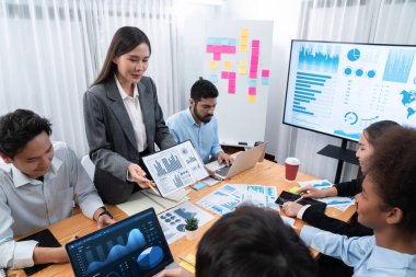 Çok ırklı analist ekibi toplantı masasındaki finansal verileri analiz etmek için BI Fintech yazılımı kullanıyor. Finansal konsol veri ekranında pazarlama göstergesi için analiz edilmiş grafikle birlikte. Uyum