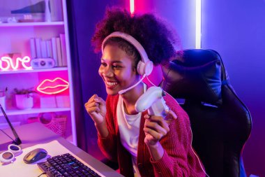 Oyun flamasının sunucu kanalı, Esport yetenekli takım oyuncusuyla yarışan Afrikalı kız ve neon renkli aydınlatma odasında online oyun izleyicileri. Siber spor ev içi aktiviteleri kavramı. Tatlandırıcı.