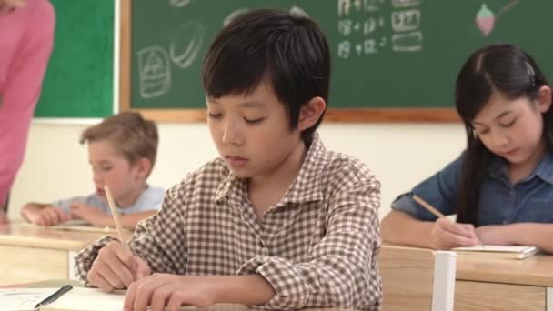 Asiatisk Smart Pojke Ler Mot Kameran Medan Eleven Skriver Svar — Stockvideo