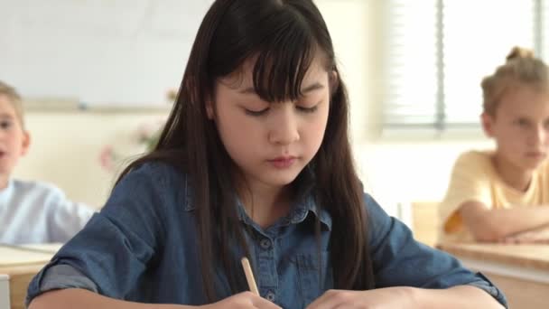 Sınav Sırasında Teoriyi Düşünmeye Odaklanırken Asyalı Kız Kağıda Cevap Yazıyor — Stok video