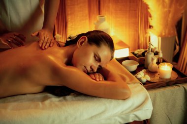 Beyaz kadın müşteri stres önleyici spa masajının keyfini çıkarıyor ve lüks otel ya da otelde sıcak mum ışığında güzellik teniyle eğleniyor. Sessiz.