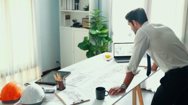 Taslak ve dizüstü bilgisayarda ayakta duran ve yazan akıllı bir mühendis. Mimarların elleri toplantı masasında ekipmanlarla birlikte yaratıcı bina inşaatını planlayıp düşünüyor. Hizalama.