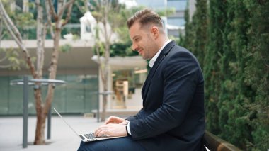 Green City 'de otururken bilgisayarla çalışan iş adamlarının yan görüntüsü. Akıllı yönetici bilgisayar yazma raporunu ve pazarlama stratejisini uzaktan kumandayla iş ekibiyle çalışırken kullanıyor. Urbane.