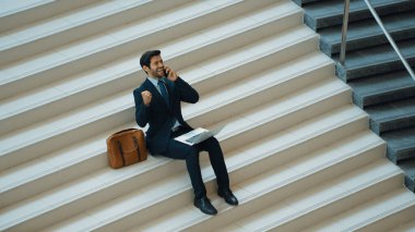 Üst düzey bir iş adamı merdivenlerde otururken başarılı bir projeyi kutluyor. Akıllı proje yöneticisinin yeni bir işe girmesi, terfi alması, telefon kullanarak arkadaşlarını arayarak satışları artırması. Sevinçli..