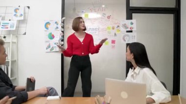 Genç liderin kapanışı, proje hakkında beyin fırtınası yapan meslektaşı ve proje yöneticisi tarafından çevrelenmiş zihin haritası ve renkli yapışkan notlar kullanılarak kendinden emin bir şekilde iş projesini sunuyor. Tertemiz..