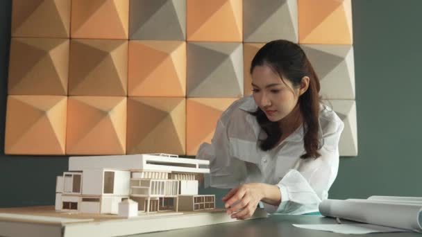 专业的亚洲女建筑工程师在检查办公室的房屋模型时的服装 检查房地产房 商业设计和建筑概念 机械手 — 图库视频影像
