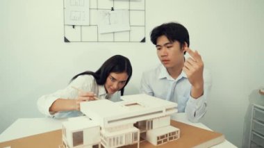 Profesyonel akıllı iş birliği mühendisi mühendis ekibi modern ofisteki ev yapısını planla kontrol ederken genç ve güzel proje yöneticisi not alıyor. Yaratıcı tasarım konsepti. Tertemiz...
