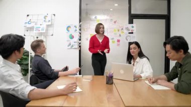 Genç liderin kapanışı, proje hakkında beyin fırtınası yapan meslektaşı ve proje yöneticisi tarafından çevrelenmiş zihin haritası ve renkli yapışkan notlar kullanılarak kendinden emin bir şekilde iş projesini sunuyor. Tertemiz..