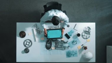 Türbin motoru veya jet motoru tasarımı ve çeşitli metal teçhizat dağılımı ile toplantı masasında yeşil ekranlı tablet üzerinde çalışırken telefona bakan mühendis görüntüsü. Hizalama.