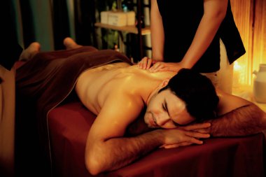 Beyaz erkek müşteri stres önleyici spa masajının keyfini çıkarıyor ve lüks otel ya da oteldeki ortam kaplıcalarında sıcak mum ışığında güzellik teniyle eğleniyor. Sessiz.