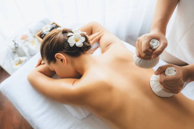 Sıcak bitkisel top spa masaj vücut tedavisi, masör kadın vücuduna nazikçe şifalı bitki torbası bastırıyor. Aromaterapi dinlenme sükuneti ve sükuneti kaplıca salonundaki atmosferi aydınlatıyor. Sessiz.