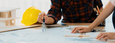 Kooperatif mimar ekibinin kesilmiş görüntüsü ev modeli, güvenlik miğferi ve mimari planlarla toplantı masasında birlikte çalışmaya karar verir ve birlikte çalışırlar. - Yakın çekim. Eline odaklan. Filizlenen.