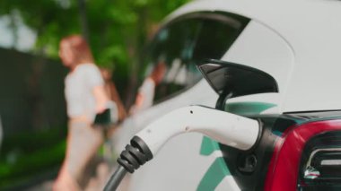Yavaş çekim odaklı EV elektrikli araba yeşil sürdürülebilir şehir açık hava bahçesinde şarj çift bulanık arka planı şehir elektrikli araç iç organları için temiz şarj edilebilir