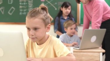 Beyaz çocuk çeşitli öğrenci kodlama mühendisliği komut ile çevrili kameraya bakarken programlama sistemine odaklanıyor. Happy öğretmen bilgisayar dersinde dizüstü bilgisayarda çalışan çocuklara destek oluyor. Pedagoji.