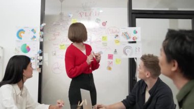Yetenekli genç ve güzel iş kadını, yaratıcı iş toplantısında yakışıklı yönetici dinlerken zihin haritalama ve istatistiksel grafik kullanarak pazarlama fikrini kendine güvenle sunuyor. Tertemiz..
