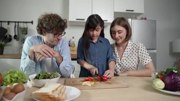 迷人的高加索父亲和母亲花时间在一起和亚洲女儿一起做新鲜的饭菜 精力充沛的爸爸妈妈在厨房准备新鲜蔬菜做沙拉 健康食品 教育学 — 图库视频影像