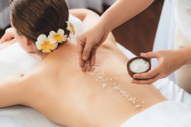 Lüks spa salonlarında sıcak mum ışığında cilt bakımı yaptıran kadın müşteri. Sağlık Spa vücut fırçasında tuz temizleme güzellik tedavisi. Sessiz.
