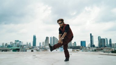 Profesyonel sokak dansçısının şehir manzaralı çatı katındaki dansçısının B-boy dans gösterisi. Çekici Asyalı hipster enerjik adımlar atıyor. Açık hava sporu 2024. ÇalışmaComment.