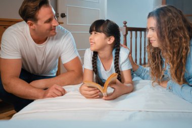 Çocukluk hikayeleri anlatan uyku zamanı, anne ve baba rahat ve rahat yatak odasındaki küçük kızlarına birlikte fantezi kitabı okuyorlar. Modern aile eğlencesi. Eşzamanlama