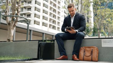 Kafkas iş adamları yeşil şehirde otururken tablet üzerinde çalışıyorlar. Uzman yönetici iş ekibiyle çalışırken finansal veri analizi yapmak ve aramak için tablet kullanıyor. Urbane.