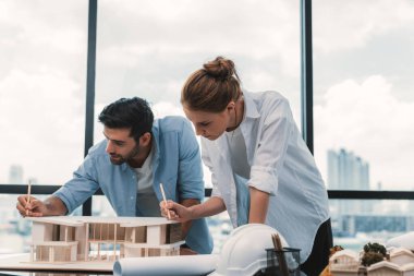 Akıllı beyaz mimar mühendis takımı ev modelini ölçmek için birlikte çalışıyor. Bir grup profesyonel iç mimar tasarım inşaatı hakkında fikir paylaşımı ve beyin fırtınası yapıyor. İzleme.