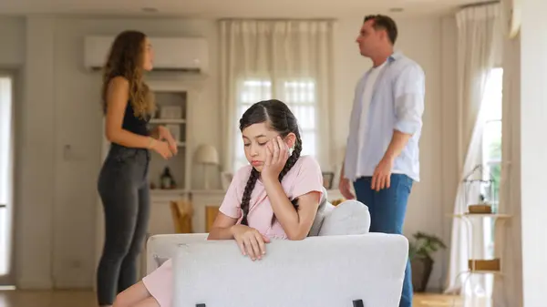 坐在沙发上 被父母在客厅里的争吵困在紧张之中的年轻姑娘生气而不高兴 不健康的家庭生活方式和受创伤的童年发展成抑郁症 — 图库照片