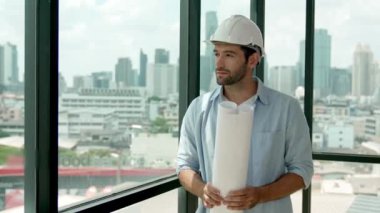 Profesyonel mühendis gökdelen manzarasına bakarken gülümsüyor. Sıradan giyinen yetenekli bir mimar, şehir manzaralı panorama penceresinin yanında dururken plan yapıyor. İzleme