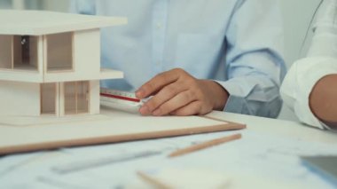 Profesyonel erkek mühendis ev modelini cetvel kullanarak ölçerken güzel bir kooperatif iş arkadaşı verileri analiz etmek için dizüstü bilgisayar kullanarak birlikte çalışıyor. Yaratıcı tasarım ve takım çalışması. - Yakın çekim. Tertemiz..