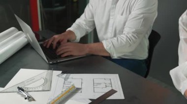 Bir grup mimar mühendis birlikte çalışıyor ve ofis tasarımı hakkında tartışıyorlar. Genç mühendis ev modelini ölçerken yönetici dizüstü bilgisayar kullanıyor. İş tasarımı konsepti. Yönlendirici.
