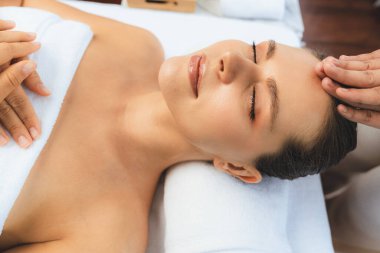 Kafkasyalı kadın stres önleyici kafa masajından ve lüks tatil beldesi ya da otel spa salonundaki modern ışık ortamında yüz güzelliği eğlencelerini şımartmaktan hoşlanıyor. Sessiz.