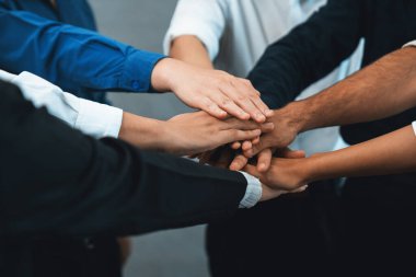 Çeşitli ofis çalışanlarından oluşan bir grup, ofis odasında el ele vererek iş sinerjisini ve iş yerindeki güçlü verimli takım çalışmasını sembolize ediyor. İş çalışanları arasındaki işbirliği ve birlik. Tedbirli