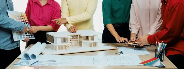 专业建筑师团队对房屋色彩选择进行了头脑风暴 而建筑师则将蓝图和房屋模型放在桌面上的蓝图文档上 — 图库照片