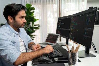 Akıllı IT geliştiricisi laptop ve iki pc ekranda kodlanan kağıtlar üzerine veri notları yazarak modern ofiste uygulama programı güncelleme sürüm sistemi yaratıyor. Tahmin et..
