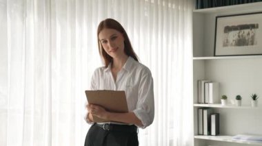 Klinikteki dost canlısı psikolog kadın. Profesyonel portresi. Kameraya bakıp psikolog muayenehanesine bakıyor. Tecrübeli ve kendinden emin psikolog.