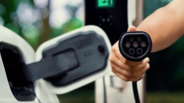 Kameranın önüne odaklanmış EV şarj cihazı fütüristik akıllı dijital EV batarya durum hologramını gösteriyor. EV araba şarjı sürdürülebilir güç için alternatif enerji kullanıyor. İnceleyin