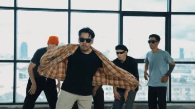 Profesyonel hipster, çeşitli çok kültürlü arkadaşlarıyla birlikte adım atıp dans ediyor. Gökyüzü dövüşçüsü ve şehir manzaralı pencerenin yanında duruyor. Break dans. Açık hava sporları konsepti 2024 hiphop..